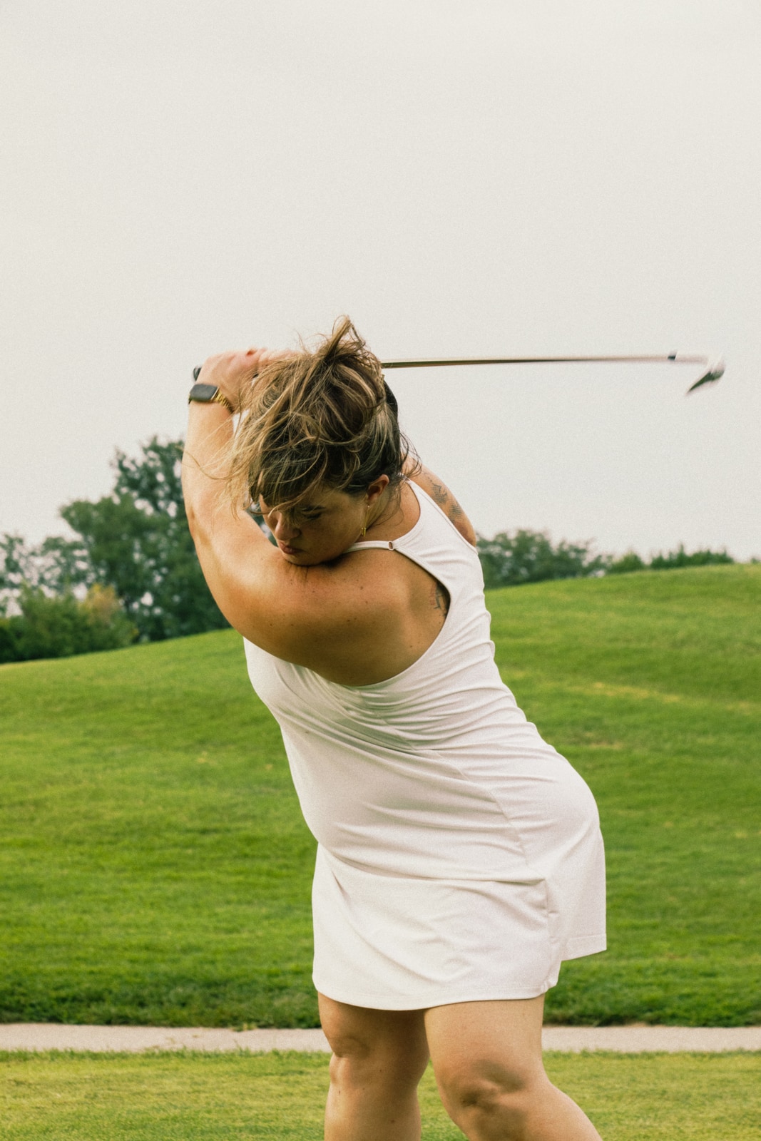 Golfer's dreadlocks flying at the top of her full swing