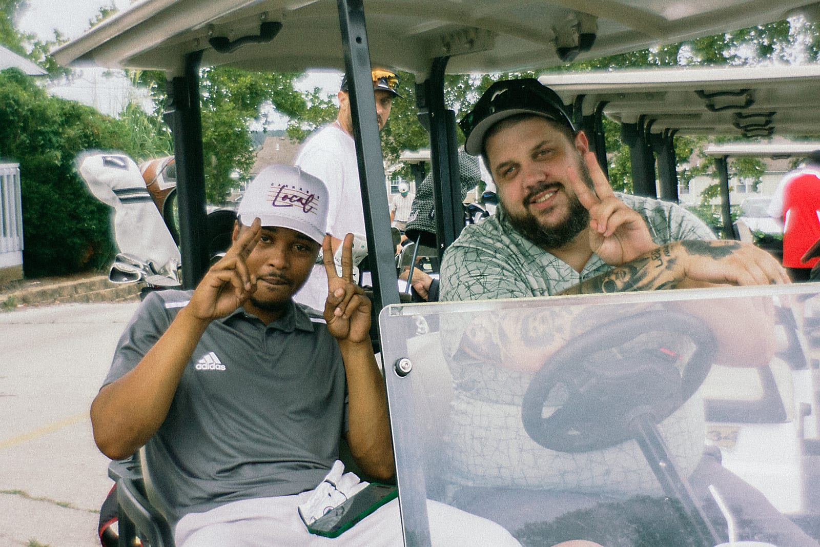Two league members throwing up peace signs from the cart