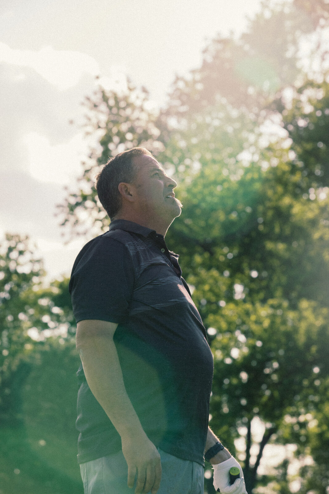 Player squinting into sun flare against trees