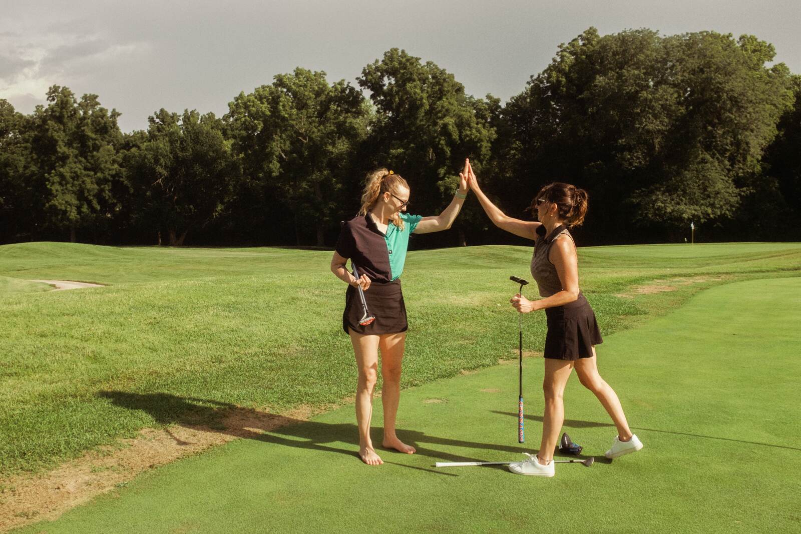 Two players high-fiving on the fairway between shots