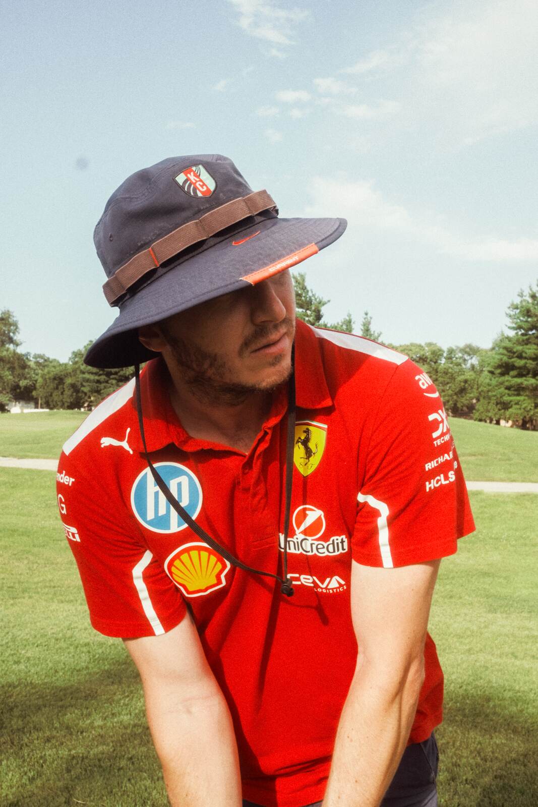 League member in a Ferrari team polo and a navy KC bucket hat leaning on his club